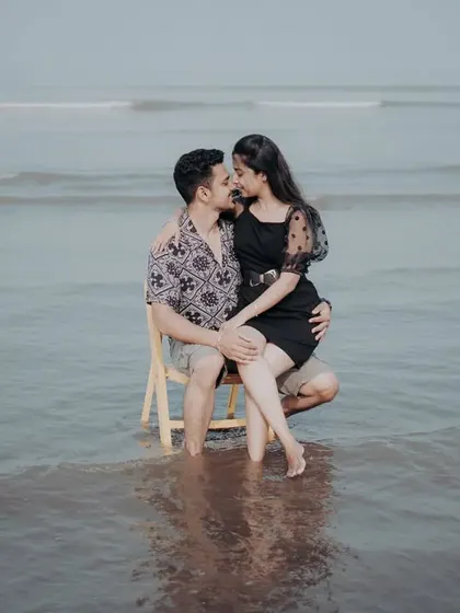 An intimate and playful pre-wedding photo of the couple on a chair in the ocean, creating a unique and memorable scene.
