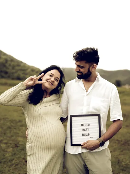 Fun and playful, this shot captures the couple's personality. Her peace sign and bright smile, paired with his proud hold on the "Hello Baby Bump" sign, make for a joyful and modern maternity portrait.