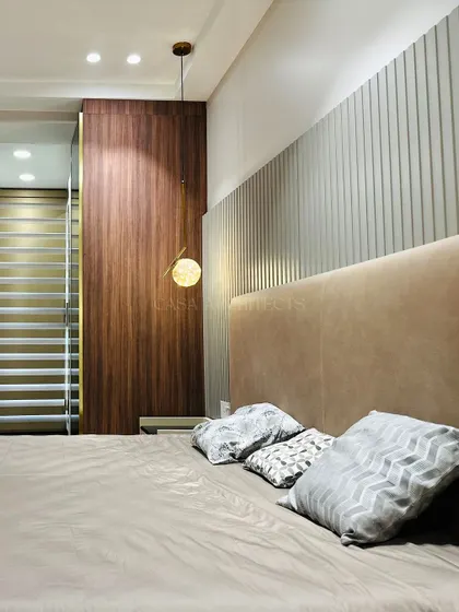 A contemporary bedroom with a unique fluted wood accent wall behind the bed. The single pendant light adds an asymmetrical and modern design element.
