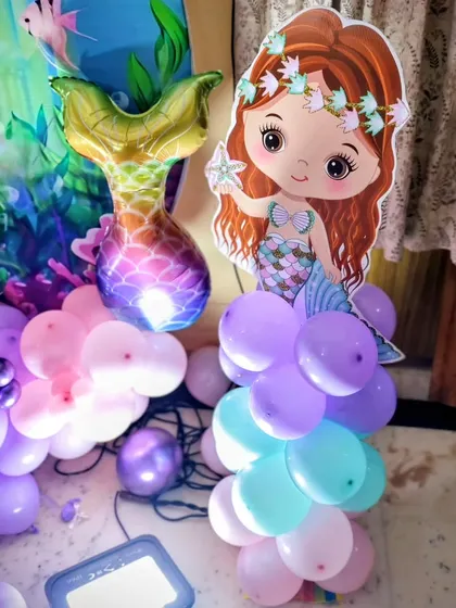 A mermaid tail foil balloon and a character cutout add fun touches to the balloon arrangement's.