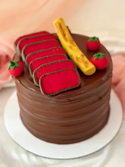 This cake is a carnivore's dream, designed to look like a perfectly cooked steak. The rich chocolate buttercream cake is decorated with fondant steak slices, a side of potatoes, and tomatoes.