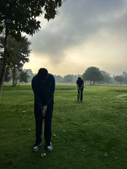 Two golfers practice their chipping in the early morning mist, dedicated to improving their game.