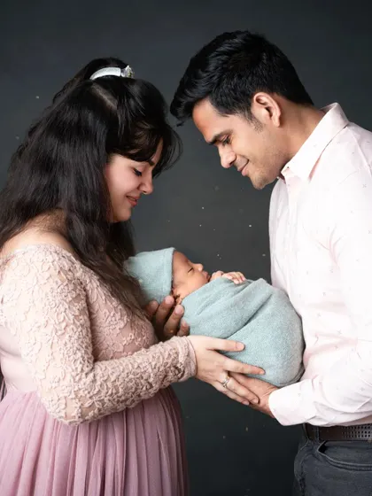 New parents sharing a quiet, intimate moment as they hold their newborn baby together.