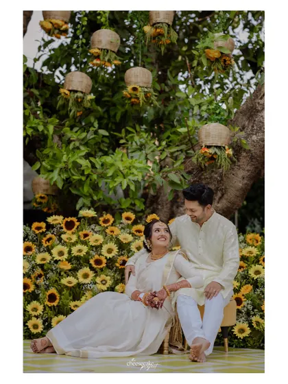 A sweet portrait of the couple seated in front of a wall of sunflowers at their Lonavala wedding.