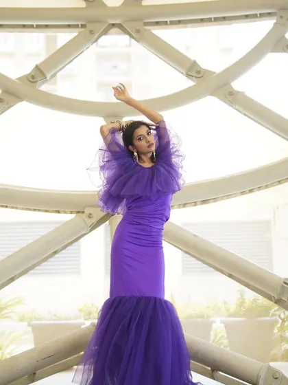 A full-length shot showcasing the dramatic silhouette of the purple mermaid gown. The makeup is bold enough to stand out and complement the entire look.
