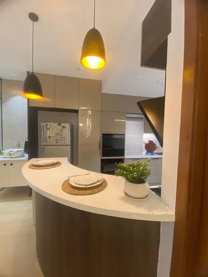 A modern kitchen with a curved breakfast bar, perfect for casual meals. The space features glossy beige cabinets, built-in appliances, and stylish pendant lights.