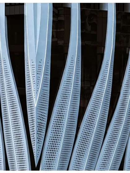 A detailed shot of the perforated facade panels, showing the gradient of perforations designed to control sunlight and create a visually interesting texture.