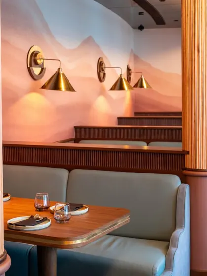 The gentle curve of our dining room, with its fluted columns and soft booth seating, creates a space that is both elegant and welcoming.