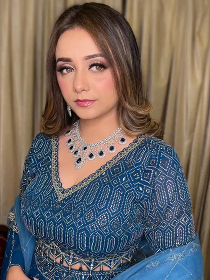 Cocktail glam with a touch of drama. The soft smokey eye and nude lip are paired with beautiful wavy hair, complementing her deep blue outfit.