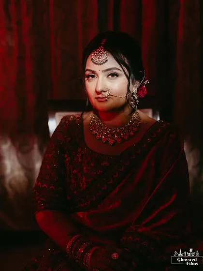 A moody, artistic portrait of the bride, Drashti, lit with red light, highlighting the rich color of her velvet shawl.