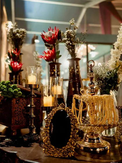 A decor vignette featuring an ornate mirror, vintage candelabras, and unique floral arrangements with proteas. These details add a touch of gothic romance to the theme.