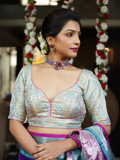 This model wears a brocade blouse with a sweetheart neckline, paired with a beautiful blue stone choker.