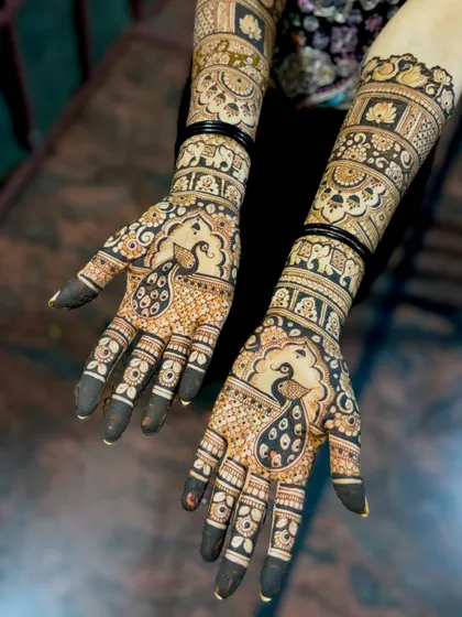 A beautiful bridal design centered around a prominent peacock motif on each palm. The feathers of the peacock are detailed with fine lines and shading.