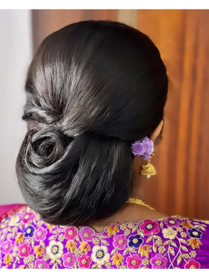 A sleek and modern rose bun for Vijayashree. This polished updo is perfect for sarees and lehengas and keeps the focus on the client's face and jewelry.