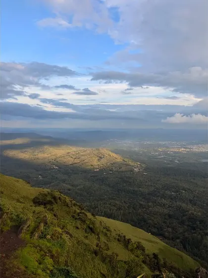 Sunlight breaking through the clouds to illuminate a patch of green forest in the Chikmagalur hills.