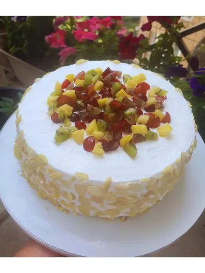 My fresh fruit cake is a celebration of summer. Topped with a colorful medley of seasonal fruits like kiwi, grapes, and pineapple, and coated with crunchy almonds, it's as beautiful as it is delicious.