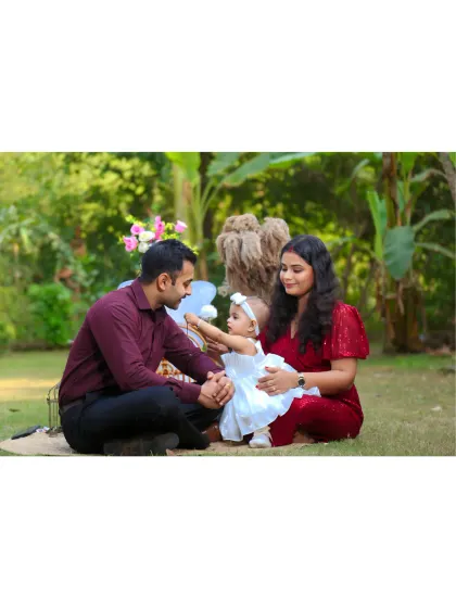 A candid family moment on the grass during their daughter's first birthday photoshoot.