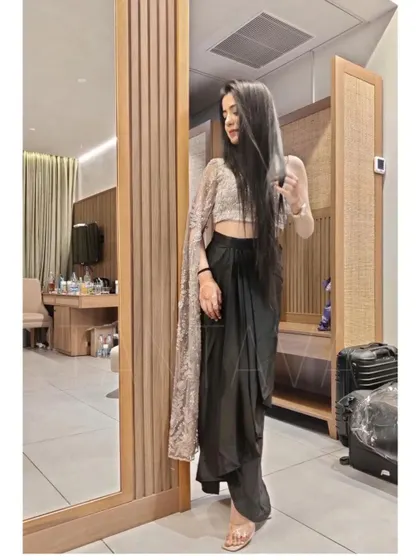 Another view of the jet black drape skirt and single-sleeve crop top, showcasing its modern silhouette and elegant flow.