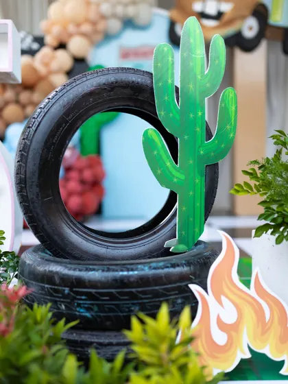A creative use of real tires as props, stacked with a cactus cutout to evoke the desert landscape of Radiator Springs from the movie Cars.