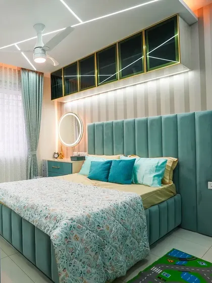 The final look of a custom-designed bedroom featuring a serene teal color palette. The fully upholstered bed with a channel-tufted headboard is complemented by matching side tables and elegant overhead storage with glass doors.