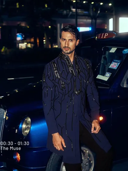 A deep navy coat with geometric, hand-embroidered lines. I designed this piece to be worn against the city lights, a modern armor for the man who navigates the night with power and sophistication.