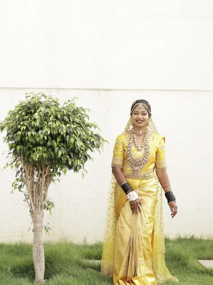 A beautiful bride in a vibrant yellow saree, paired with a custom blouse featuring delicate gold embroidery.