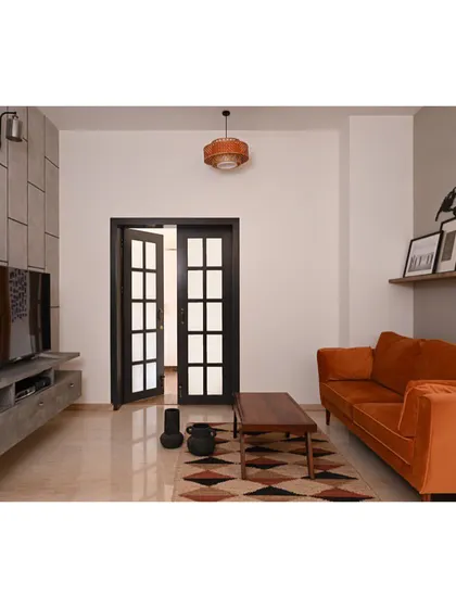 In this TV lounge, we used a more somber palette for a cozy, modern feel. A grey wall panel and TV unit are balanced by the warmth of a rust-orange velvet sofa and an auburn-toned carpet.