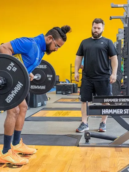 A UKSCA assessor provides detailed feedback on a bent-over row, a crucial exercise for back strength and posture.