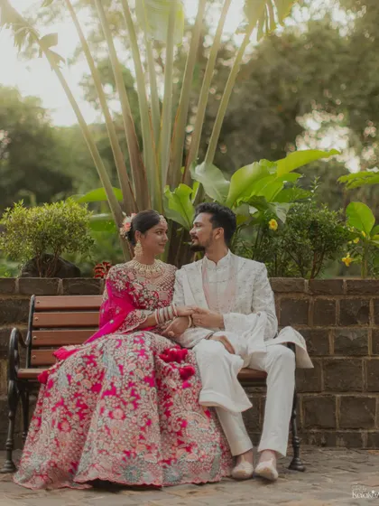 A serene portrait of the couple in their stunning wedding attire, sharing a quiet moment on a park bench.