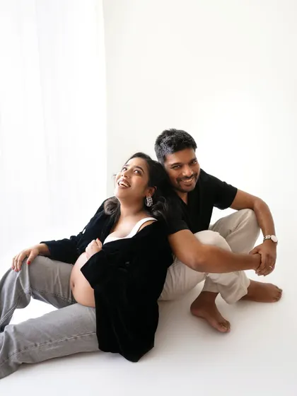 A fun and relaxed pose, sitting back-to-back. This shows the couple's playful side and their partnership as they wait for their little one to arrive.