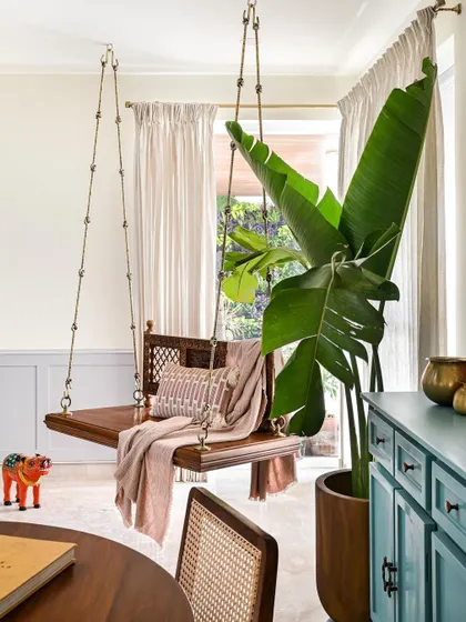 A traditional wooden swing, or 'oonjal', brings a sense of heritage and comfort to this living space. It's a perfect spot for lounging with a book.