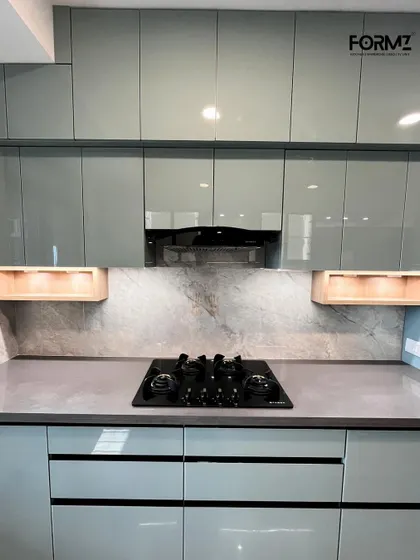 A close-up of the cooking zone, featuring a built-in hob and a concealed chimney. The handleless drawers and cabinets maintain the kitchen's sleek profile, while wooden niches add a touch of warmth.