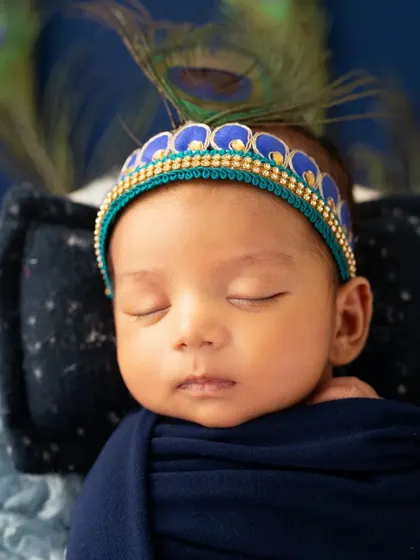 A detailed close-up of the newborn Krishna's face, highlighting the beautiful crown and peaceful expression.
