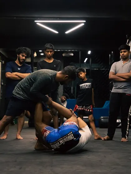 A coach demonstrates a submission from the guard position as students watch and learn.