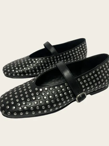 A clean product shot of the black studded ballet flats with a single strap and buckle. This angle highlights the craftsmanship and the dense pattern of the hand-applied studs that cover the shoe.