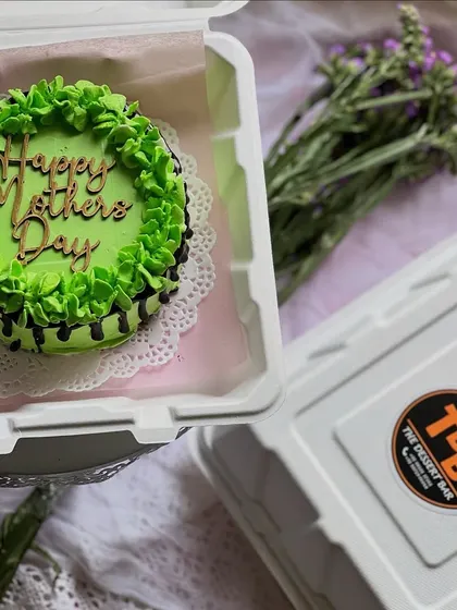 A vibrant green bento cake with a 'Happy Mother's Day' topper. The chocolate drip detail adds a little extra touch of indulgence to this special mini cake.