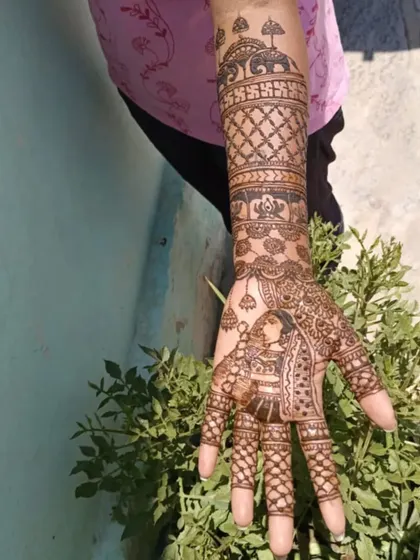A full-hand view of a bridal design. The palm features a bride's portrait, while the arm has traditional elephant motifs and a swastika symbol for good luck.