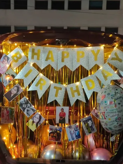 This car trunk surprise uses a glittering "Happy Birthday" banner, a gold fringe curtain, and photos to create a dazzling and personal celebration.
