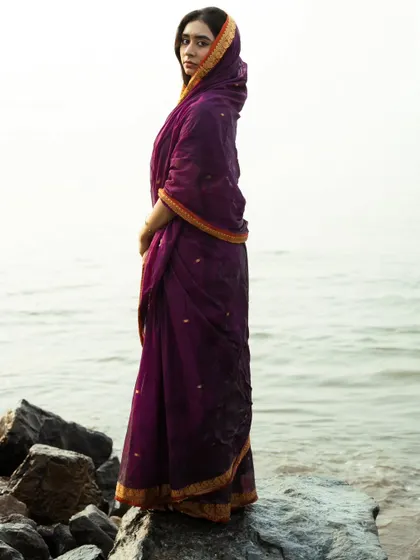 A profile shot that highlights the traditional way the saree is draped, with the endless sea as a simple, beautiful background.