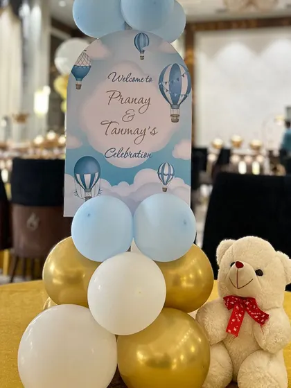 A cute table centerpiece with a teddy bear, balloons, and a personalized welcome sign.
