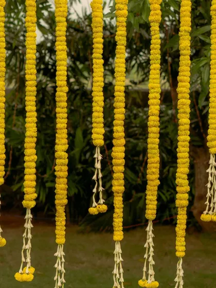 A close-up of the hanging marigold and tuberose garlands. Using local, seasonal flowers is a core part of my sustainable approach to decor, adding natural beauty and fragrance.