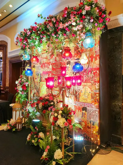An angled view of the colorful photo corner, highlighting the layers of flowers, lanterns, and textiles. The warm lighting creates an inviting and richly detailed spot for guest photos.