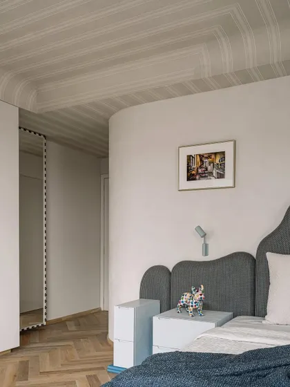 The master bedroom is a tranquil retreat. We used a bold patterned wallpaper on the curved ceiling and a custom-designed headboard to create a space that feels serene and unique.