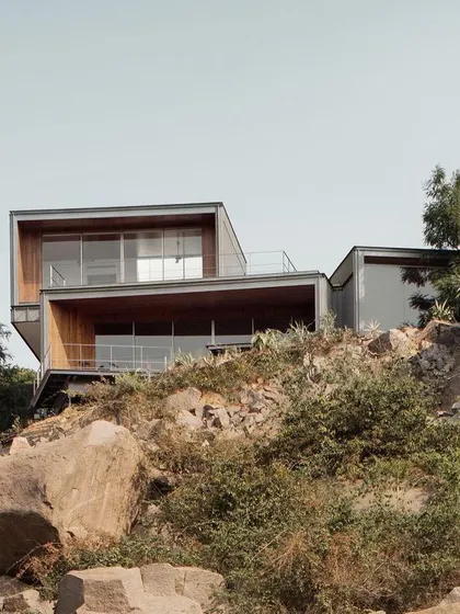 The Lakehouse in Hyderabad is perched on a rocky hill, with its distinct portals oriented to frame specific views of the lake and the city. The structure is designed to touch the ground lightly, preserving the natural terrain.