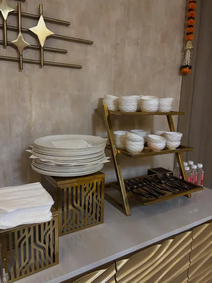 A neat and tidy crockery station for a house party, featuring stacked plates, bowls, and cutlery organized for guest convenience.