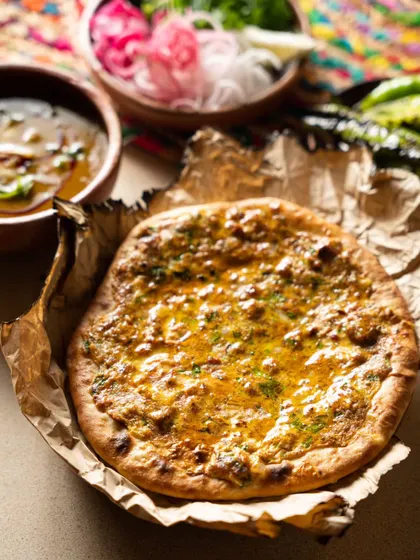 A shot of a stuffed naan, presented on parchment paper. The composition is rustic and appealing.