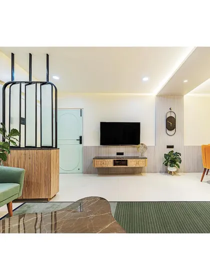 A modern living room with a mix of bold colors and textures. The green sofa, mustard yellow couch, and fluted partition create a dynamic and visually interesting space.