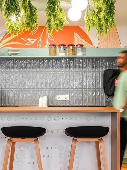 This stylish pantry area combines functionality with biophilic design. A pressed-tin backsplash, hanging greenery, and a custom mural create a refreshing spot for a coffee break.