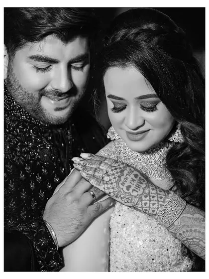 A tender black and white portrait of the couple. This close-up focuses on the bride's intricate mehndi and the couple's gentle interaction, creating a timeless and emotional image.