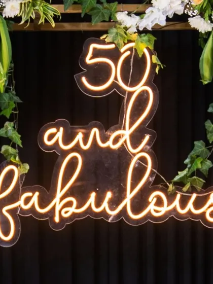 Hitting half a century in style. This "50 and fabulous" neon sign, framed by fresh ivy, was a perfect photo backdrop and a central piece of the decor, celebrating a major milestone with flair.